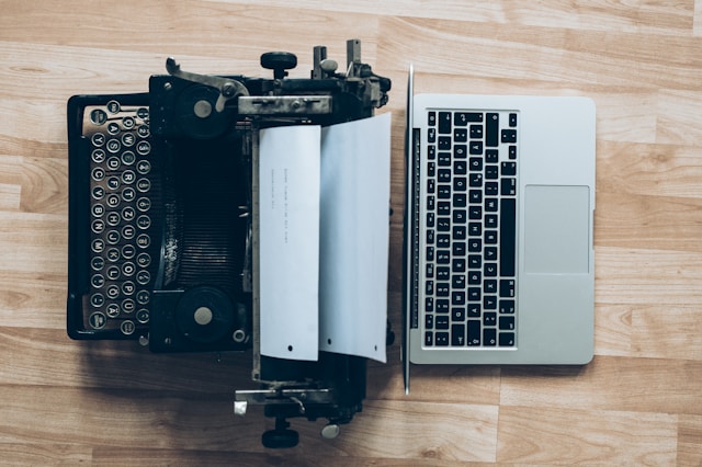 Old typewriter next to modern laptop